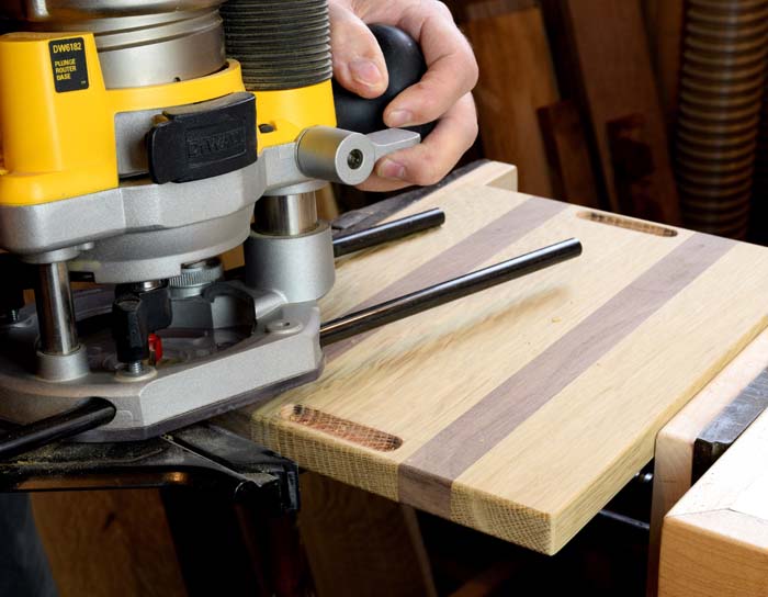 router being lifted up after routing a small finger slot in the wooden panel