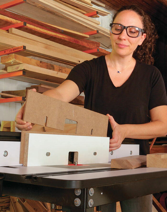 The author holds spacers which fit behind the router table fence.