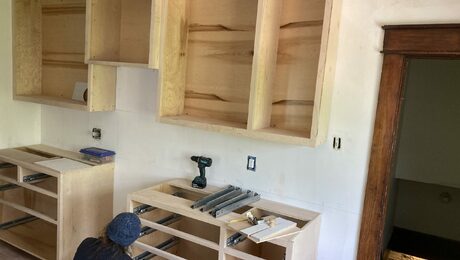 a craftsperson bent down installing something in a kitchen that is being renovated